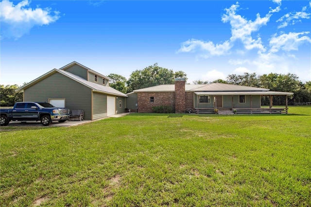 back of house with a garage, a yard, covered porch, and an outdoor structure