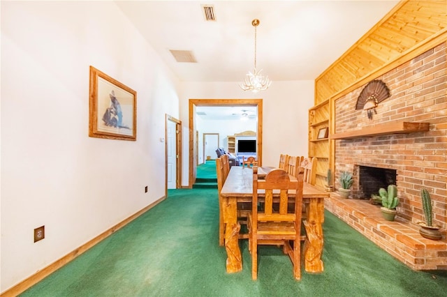 dining space featuring dark colored carpet, a notable chandelier, brick wall, and a brick fireplace