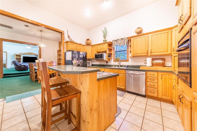 kitchen featuring light brown cabinetry, a breakfast bar area, a center island, light tile patterned flooring, and stainless steel appliances