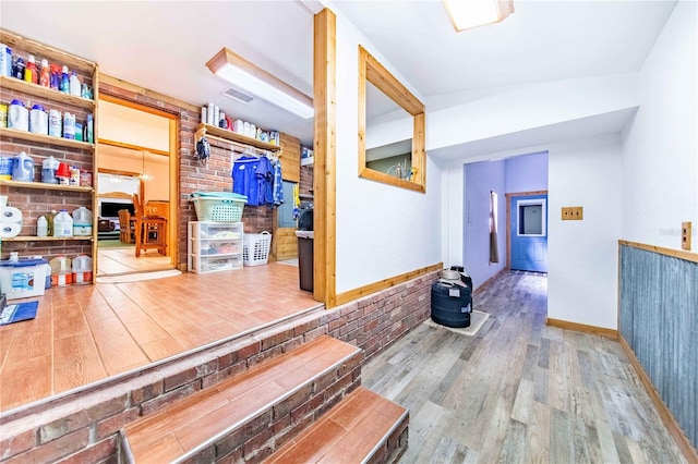 hallway with brick wall, baseboards, and wood finished floors