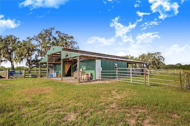 back of house featuring a rural view, an outbuilding, and a yard