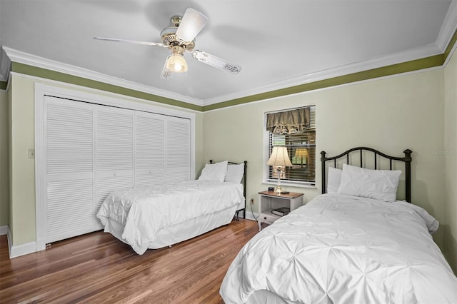 bedroom featuring dark wood-type flooring, a closet, ceiling fan, and ornamental molding