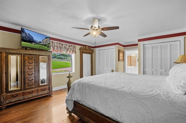 bedroom featuring two closets, ceiling fan, hardwood / wood-style floors, and crown molding