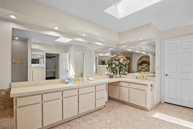 bathroom with tile patterned floors, a skylight, and vanity