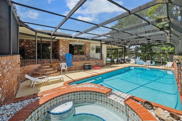 view of swimming pool with glass enclosure, an in ground hot tub, and a patio area