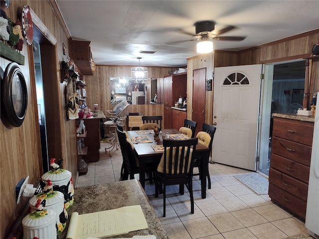 tiled dining area featuring wood walls and ceiling fan