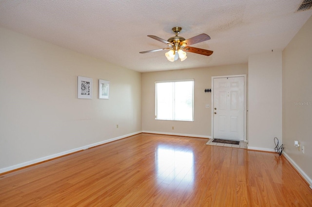 unfurnished room featuring a textured ceiling, light hardwood / wood-style flooring, and ceiling fan