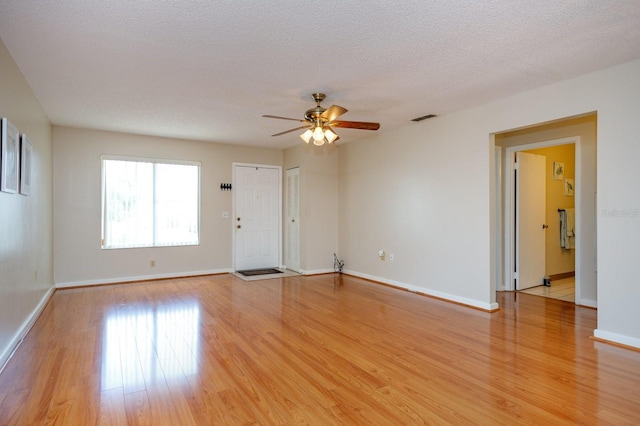 spare room with a textured ceiling, light hardwood / wood-style flooring, and ceiling fan