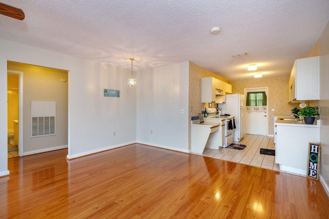 kitchen featuring light hardwood / wood-style floors, a textured ceiling, and range with electric stovetop