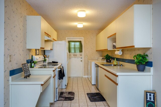 kitchen with light tile patterned floors, sink, white range with electric stovetop, washer / dryer, and a textured ceiling