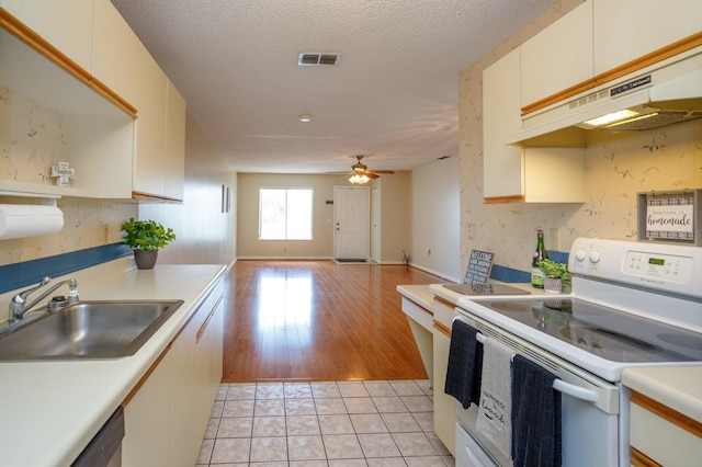 kitchen featuring electric stove, a textured ceiling, light hardwood / wood-style flooring, sink, and ceiling fan