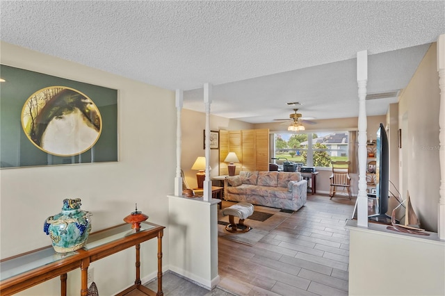 living room featuring a textured ceiling, ceiling fan, and hardwood / wood-style floors