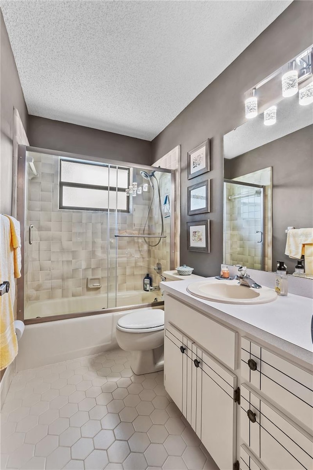 full bathroom with vanity, toilet, a textured ceiling, and bath / shower combo with glass door