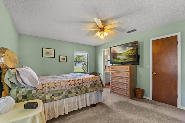 carpeted bedroom with a textured ceiling, ceiling fan, and ensuite bath