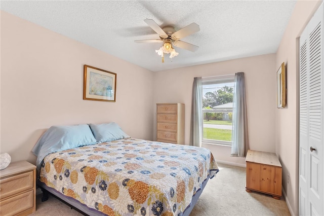 carpeted bedroom with a closet, ceiling fan, and a textured ceiling