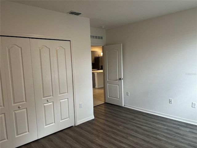 177 Cimarron Ln, Kissimmee, FL 34759 - unfurnished bedroom with dark wood finished floors, baseboards, a closet, and freestanding refrigerator
