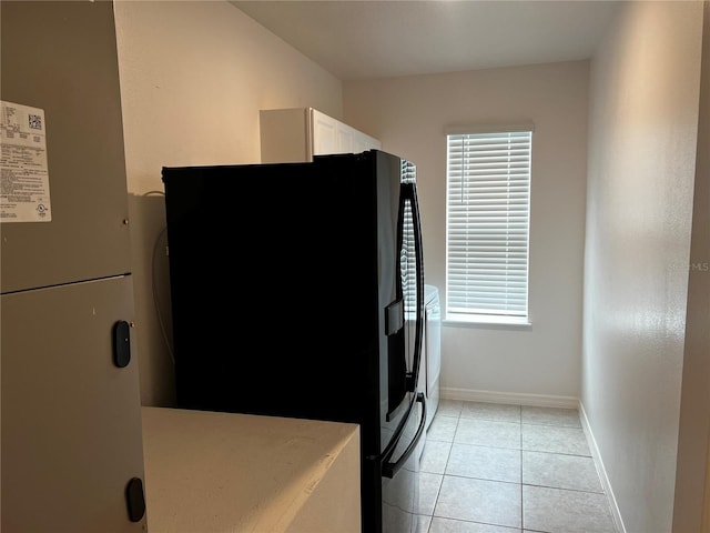 177 Cimarron Ln, Kissimmee, FL 34759 - kitchen with black fridge with ice dispenser, freestanding refrigerator, white cabinetry, baseboards, and light tile patterned flooring