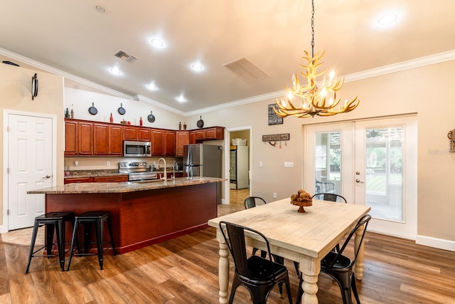 dining space with hardwood / wood-style floors, crown molding, sink, a chandelier, and lofted ceiling