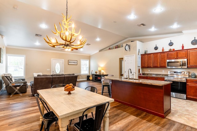 dining room with vaulted ceiling, a notable chandelier, crown molding, sink, and light wood-type flooring