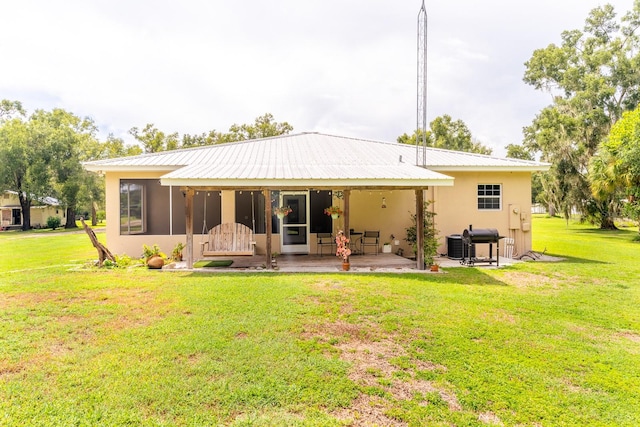 rear view of property featuring a yard, a patio area, and a sunroom