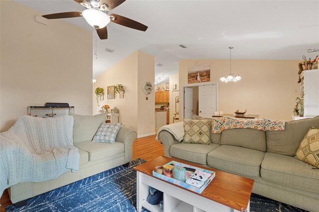 living room featuring lofted ceiling, hardwood / wood-style floors, and ceiling fan with notable chandelier