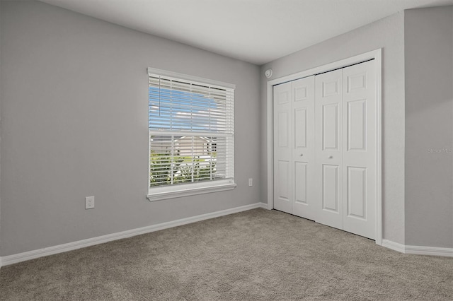 unfurnished bedroom featuring light colored carpet and a closet