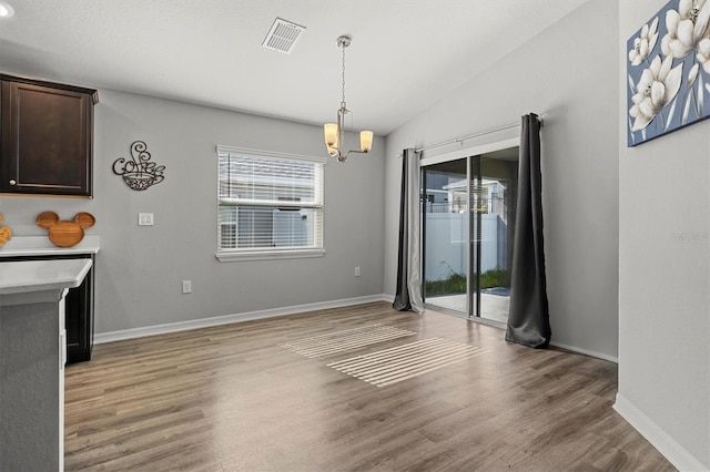 unfurnished dining area with light wood-type flooring, vaulted ceiling, and a wealth of natural light