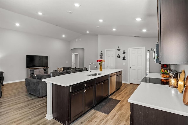 kitchen featuring lofted ceiling, dishwasher, sink, and a kitchen island with sink