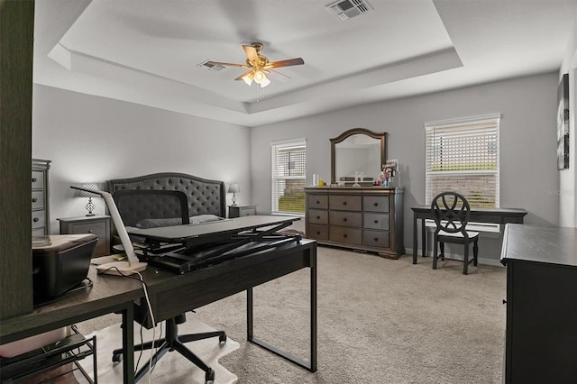 office featuring a tray ceiling, carpet floors, and ceiling fan