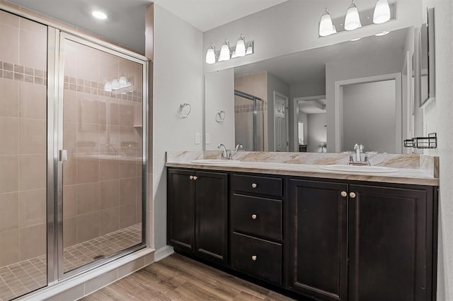 bathroom with a shower with shower door, hardwood / wood-style floors, and vanity