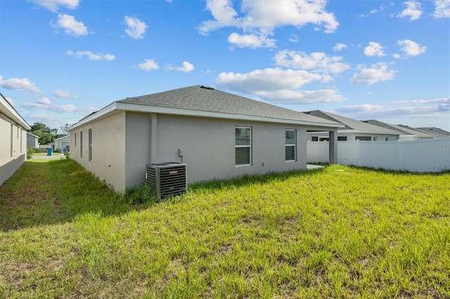 back of house featuring a lawn and central air condition unit