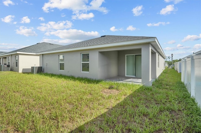 rear view of property featuring a lawn and central air condition unit