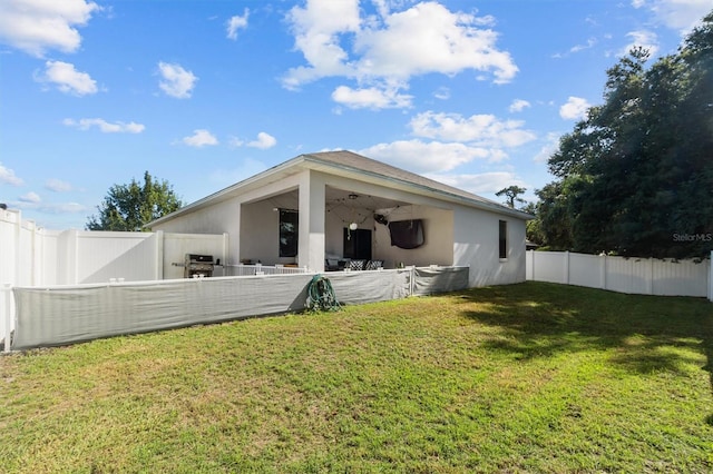 back of property featuring a yard and ceiling fan