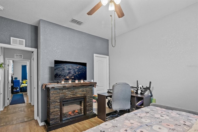 bedroom featuring a textured ceiling, ceiling fan, and a fireplace