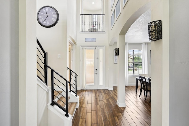 entryway featuring dark wood-type flooring and a towering ceiling