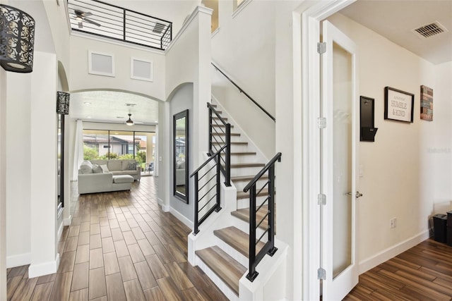 entryway with a towering ceiling, dark hardwood / wood-style flooring, and ceiling fan