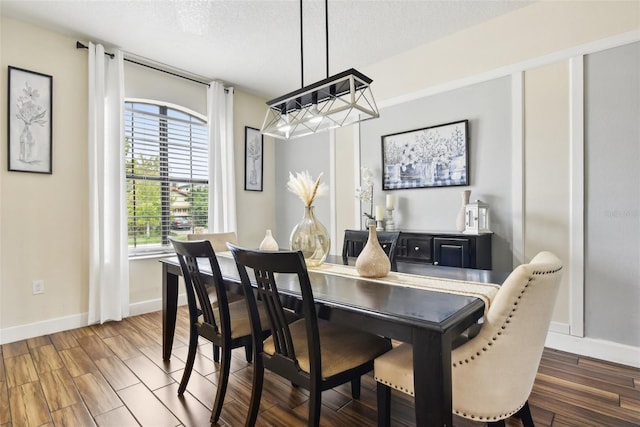 dining area featuring a chandelier, dark hardwood / wood-style flooring, and a textured ceiling