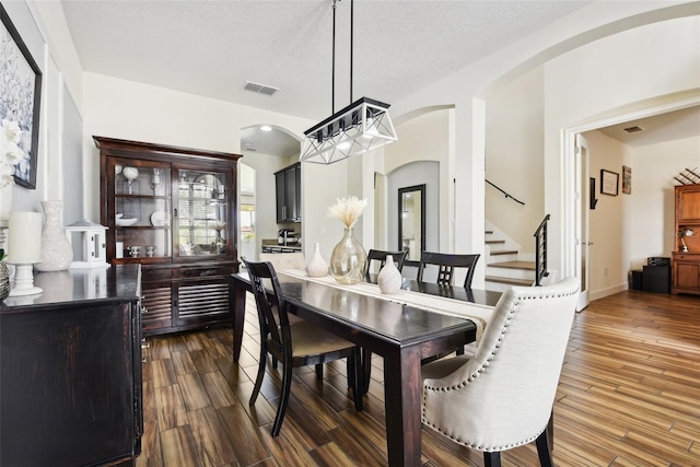 dining space featuring dark hardwood / wood-style floors, a notable chandelier, and a textured ceiling