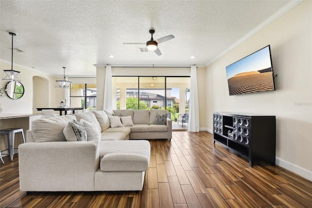 living room with ceiling fan, dark hardwood / wood-style flooring, crown molding, and a textured ceiling