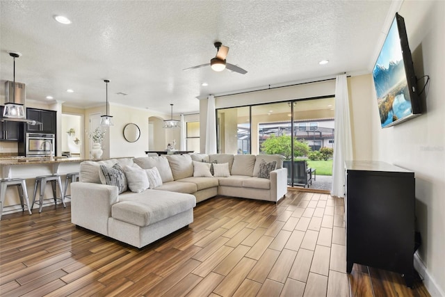 living room featuring a textured ceiling, ceiling fan, and wood-type flooring