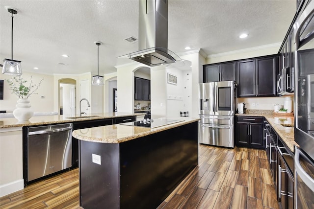 kitchen with decorative light fixtures, appliances with stainless steel finishes, a center island, and dark hardwood / wood-style floors