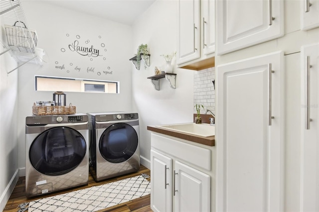 laundry area with cabinets, washer and clothes dryer, sink, and wood-type flooring