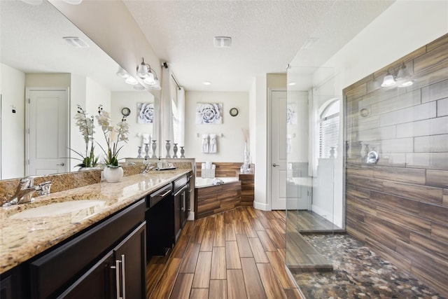 bathroom with vanity, a textured ceiling, hardwood / wood-style flooring, and a shower