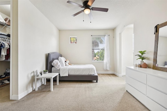 carpeted bedroom featuring a closet, ceiling fan, and a textured ceiling