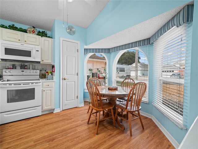 kitchen with a textured ceiling, white appliances, white cabinets, and light hardwood / wood-style floors