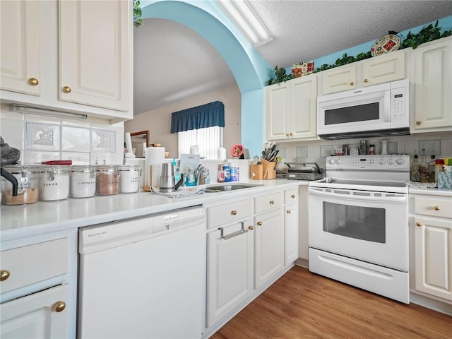 kitchen with white cabinetry, light wood-type flooring, white appliances, and a textured ceiling