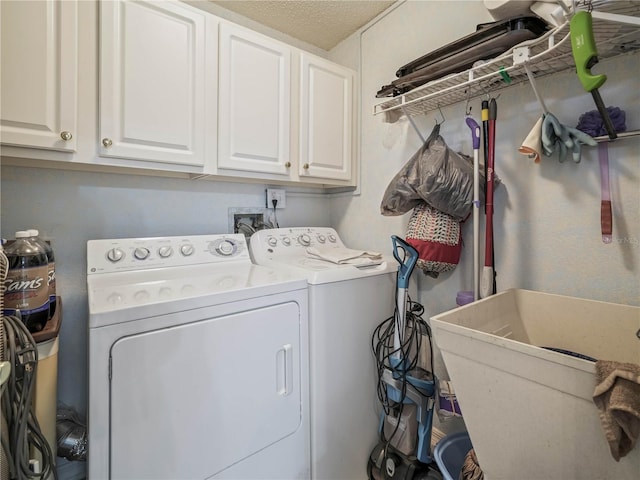 washroom with a textured ceiling, washing machine and dryer, cabinets, and sink