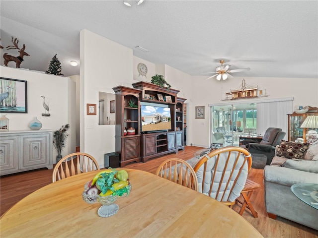 dining area with lofted ceiling, ceiling fan, light wood-type flooring, and a textured ceiling