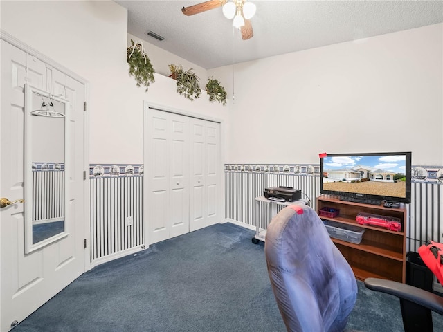 home office featuring a textured ceiling, dark carpet, and ceiling fan