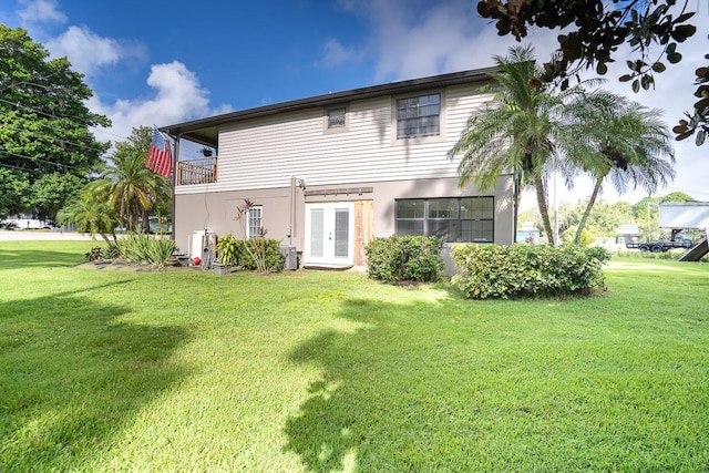 back of house featuring a lawn, a balcony, and central air condition unit